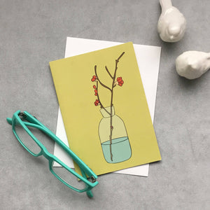  A Greeting card with flower blossoms set in a vase. flatlay