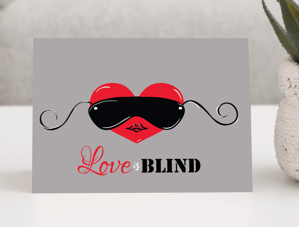 Love is Blind greeting card featuring a red heart wearing stylish black sunglasses with swirling arms on a gray background. 